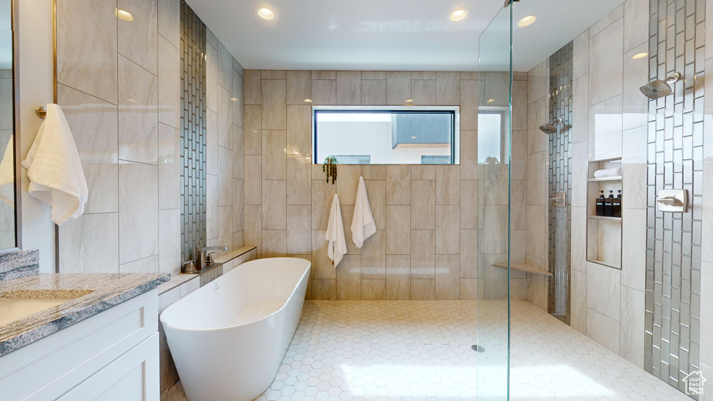 Bathroom featuring tile walls, tile patterned flooring, vanity, and separate shower and tub