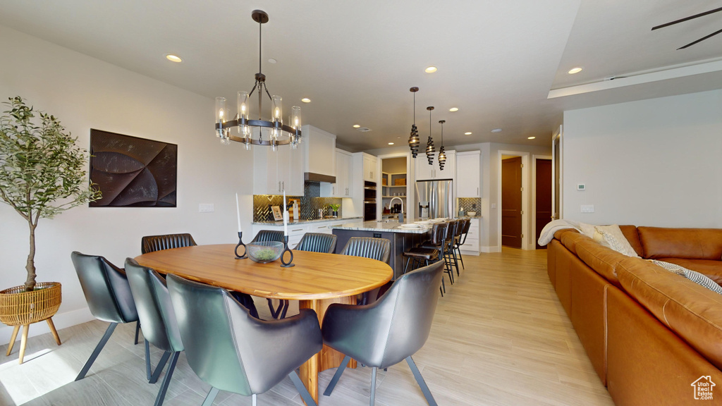 Dining room featuring light wood-type flooring, sink, and a notable chandelier