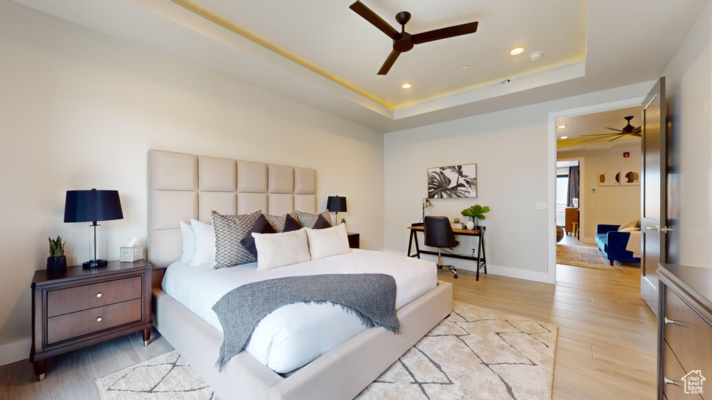 Bedroom featuring a raised ceiling, light hardwood / wood-style floors, and ceiling fan