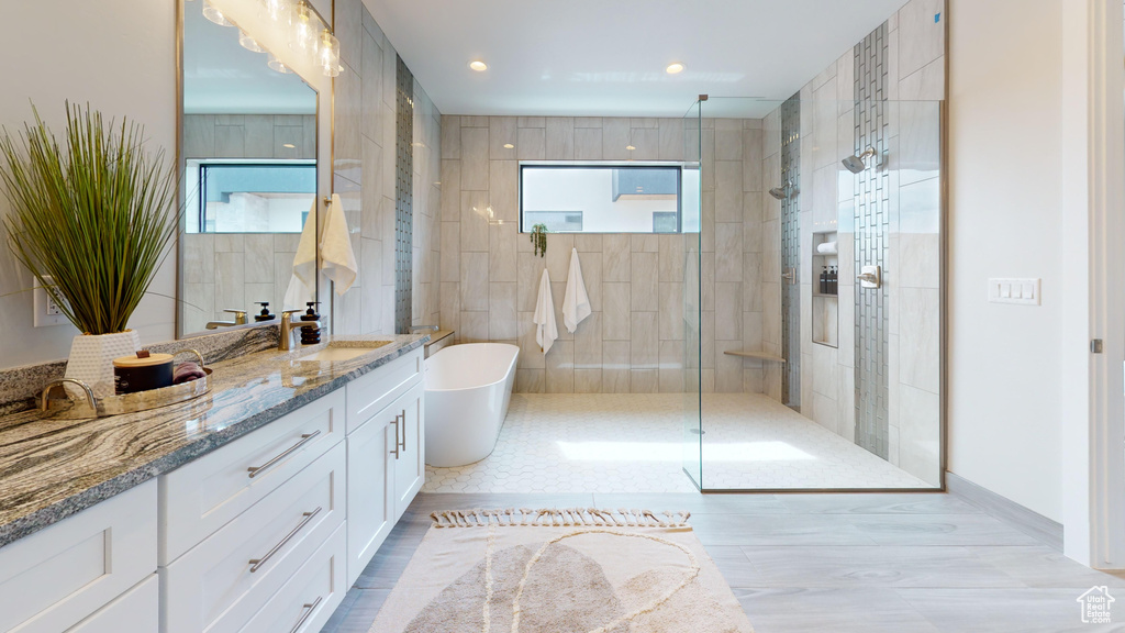 Bathroom featuring shower with separate bathtub and vanity