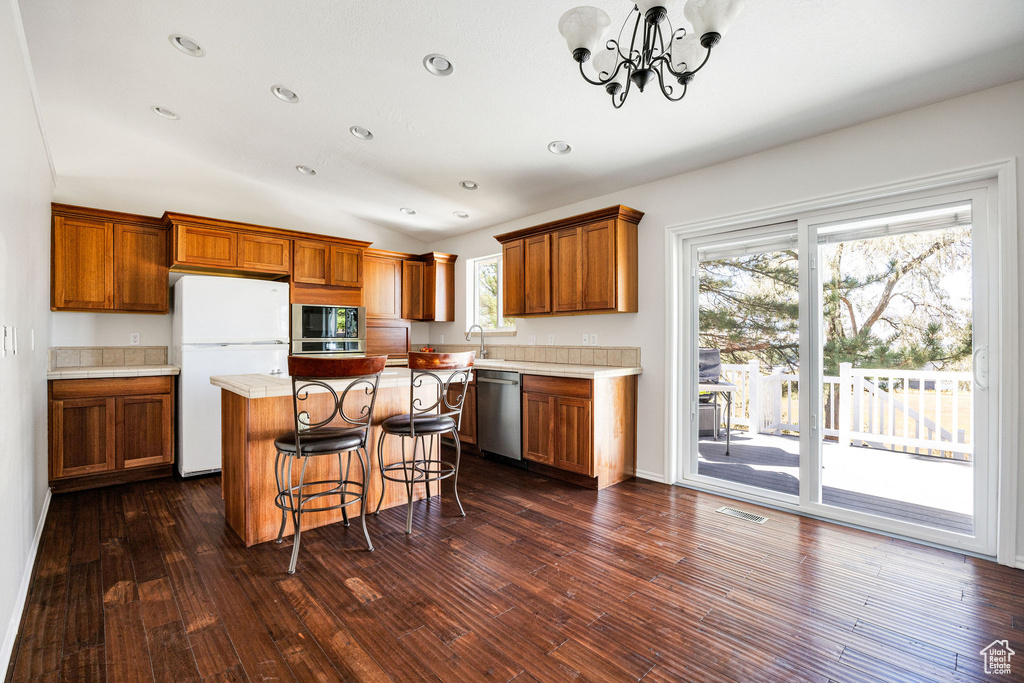 Kitchen with a kitchen island, a notable chandelier, stainless steel appliances, and a healthy amount of sunlight