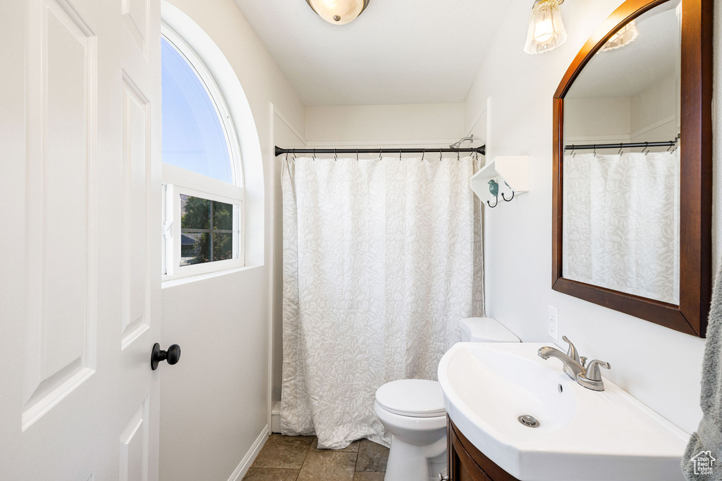 Bathroom featuring curtained shower, vanity, toilet, and tile patterned floors
