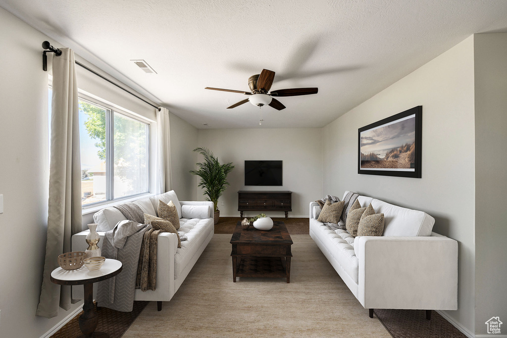 Carpeted living room with a textured ceiling and ceiling fan