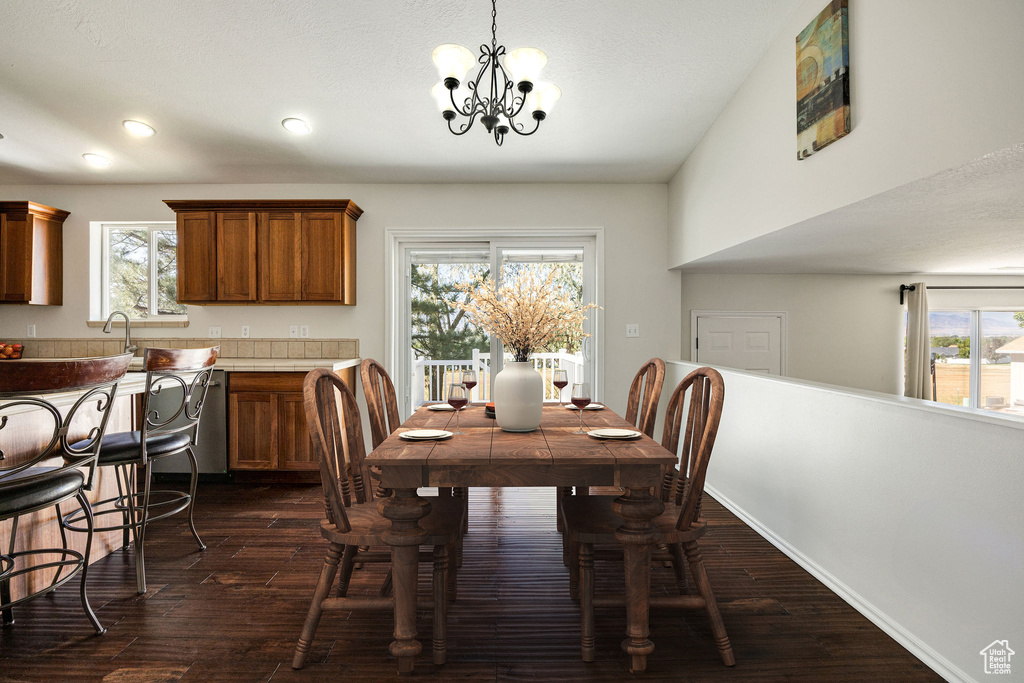 Dining space with a notable chandelier, a healthy amount of sunlight, and dark hardwood / wood-style flooring
