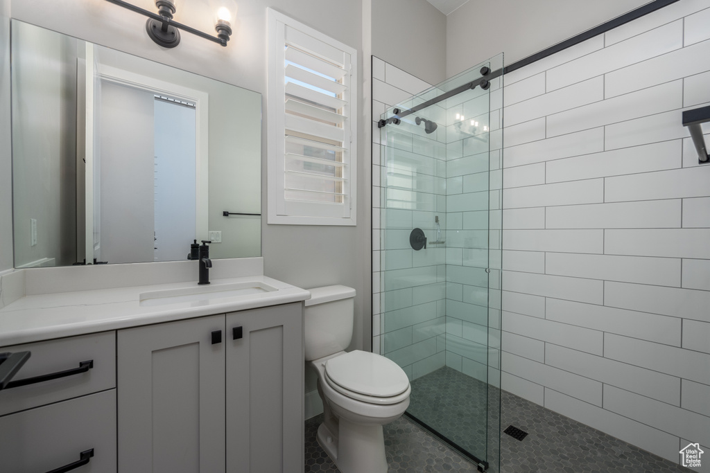 Bathroom with vanity, a shower with shower door, and toilet