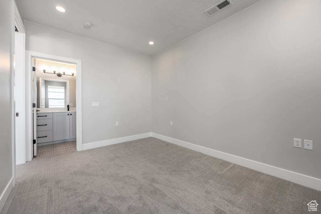 Unfurnished bedroom with light carpet and ensuite bathroom