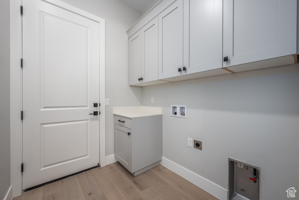 Laundry area with washer hookup, cabinets, light hardwood / wood-style floors, and electric dryer hookup