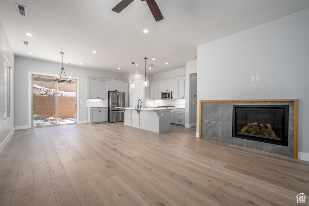 Unfurnished living room featuring light wood-type flooring, sink, and ceiling fan