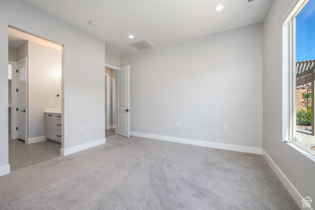 Unfurnished bedroom featuring connected bathroom and light colored carpet