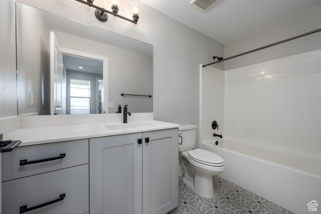 Full bathroom featuring vanity, toilet, tile patterned floors, and tiled shower / bath