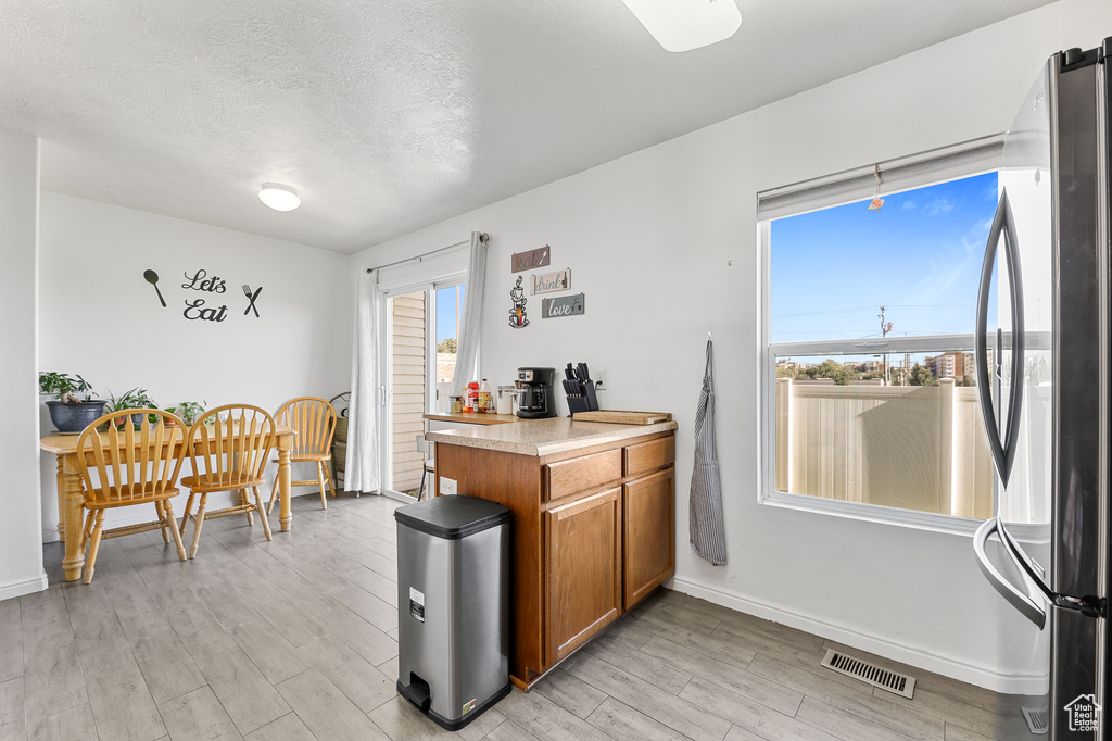 Kitchen featuring a textured ceiling, light hardwood / wood-style floors, and stainless steel refrigerator