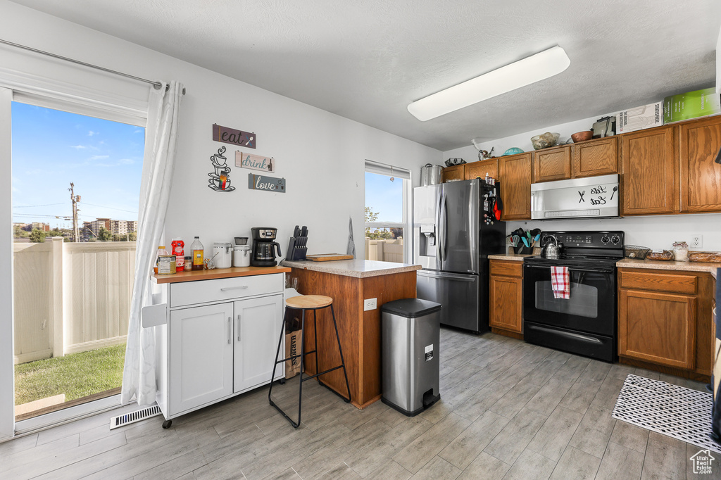 Kitchen featuring stainless steel fridge, light hardwood / wood-style flooring, and black range with electric stovetop