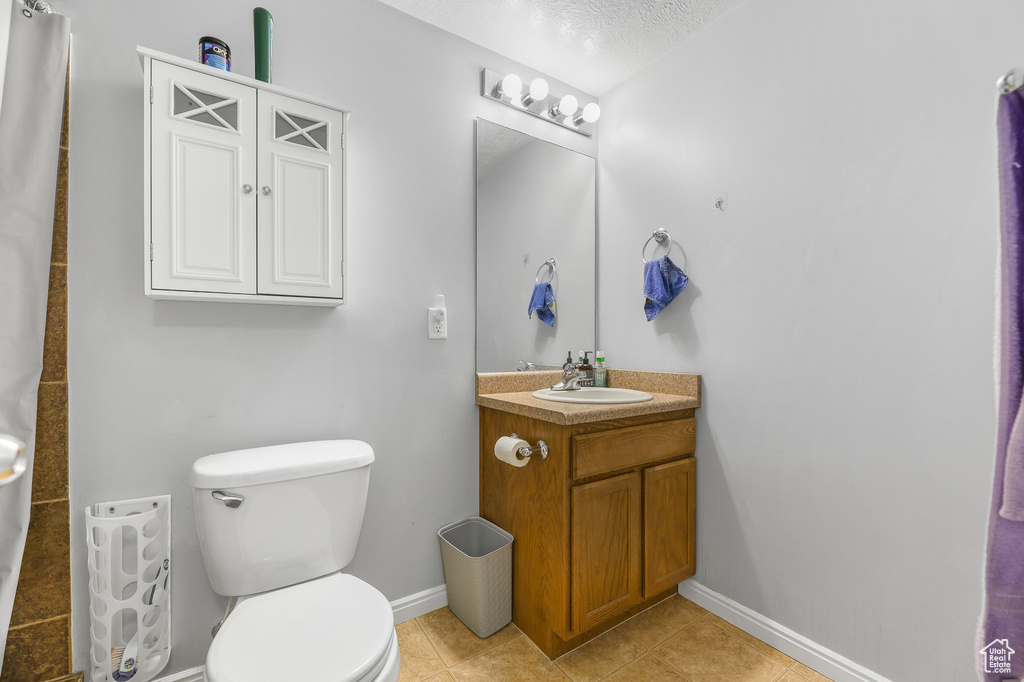 Bathroom featuring vanity, a textured ceiling, toilet, and tile patterned floors