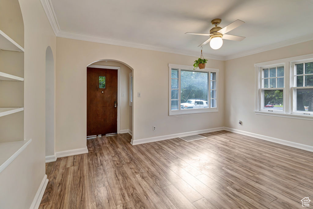 Entryway with light hardwood / wood-style floors, ornamental molding, and ceiling fan