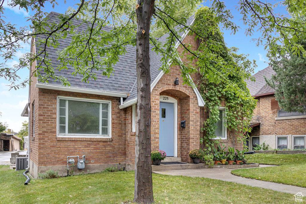 English style home featuring a front lawn and central AC unit