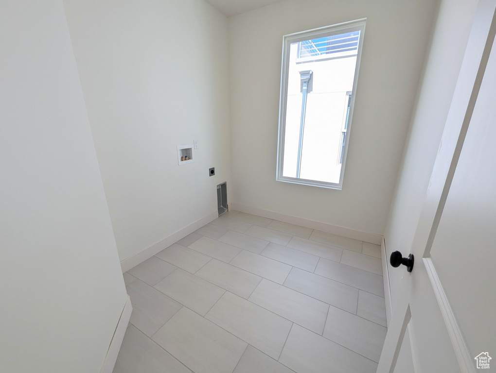 Washroom featuring hookup for a washing machine, hookup for an electric dryer, and light tile patterned floors