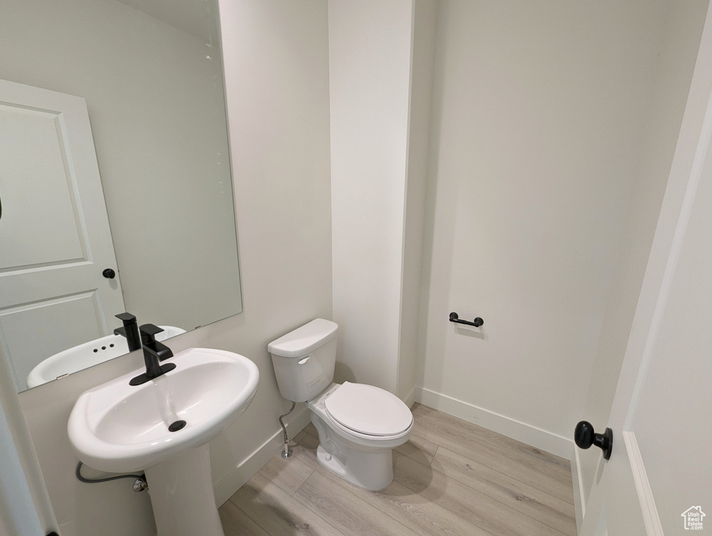 Bathroom featuring wood-type flooring, sink, and toilet