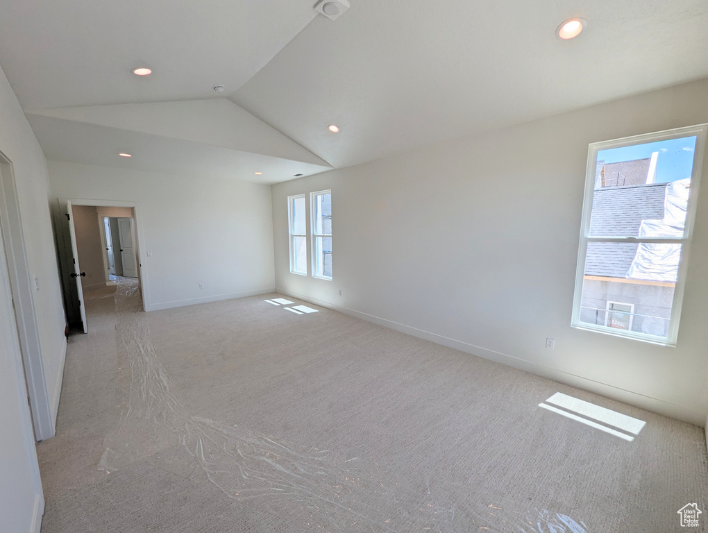 Spare room featuring light carpet and vaulted ceiling