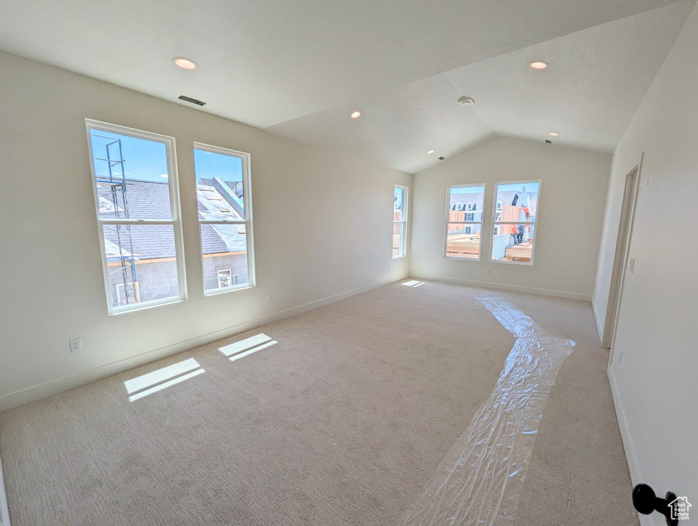 Carpeted spare room featuring lofted ceiling