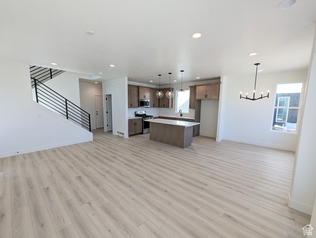 Kitchen featuring light wood-type flooring, a center island, stainless steel appliances, and a wealth of natural light