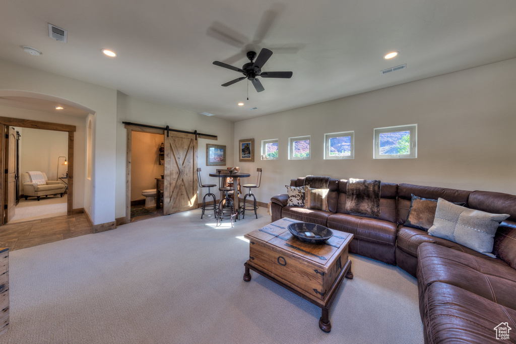Carpeted living room with a barn door and ceiling fan