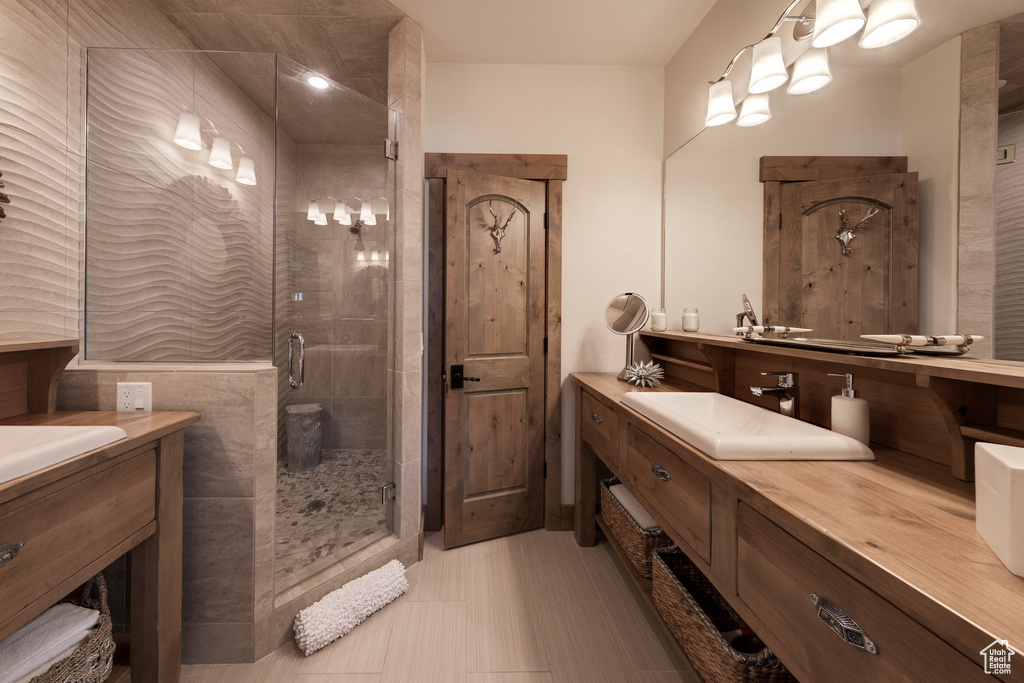 Bathroom featuring tile patterned floors, walk in shower, and vanity