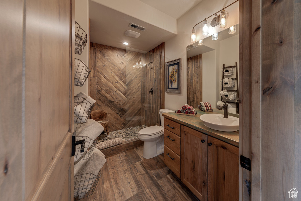 Bathroom featuring a shower, vanity, toilet, and hardwood / wood-style flooring