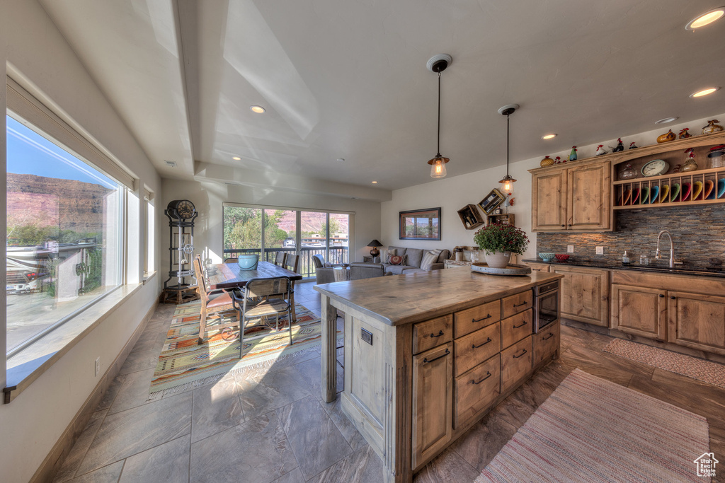 Kitchen with pendant lighting, a center island, a breakfast bar area, sink, and decorative backsplash