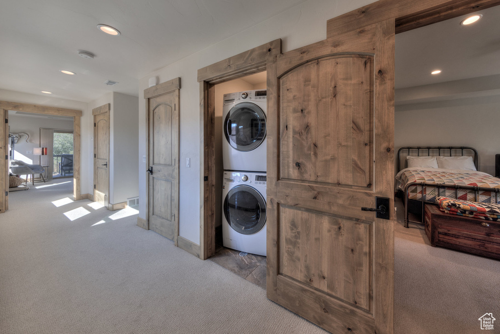Washroom featuring stacked washer and clothes dryer and light carpet