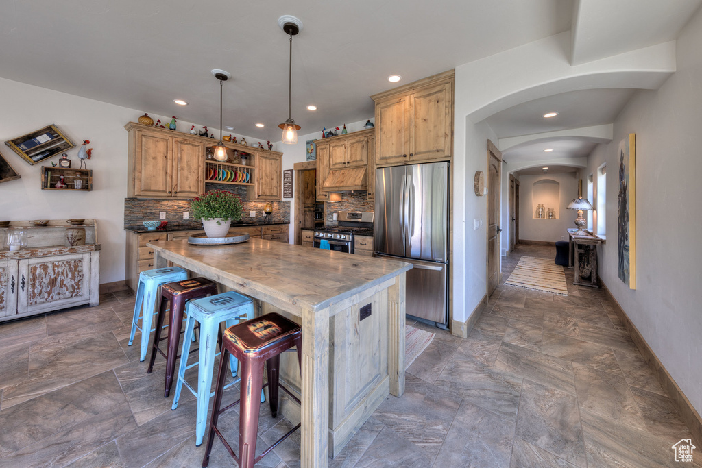 Kitchen featuring pendant lighting, butcher block counters, a kitchen island, stainless steel appliances, and backsplash