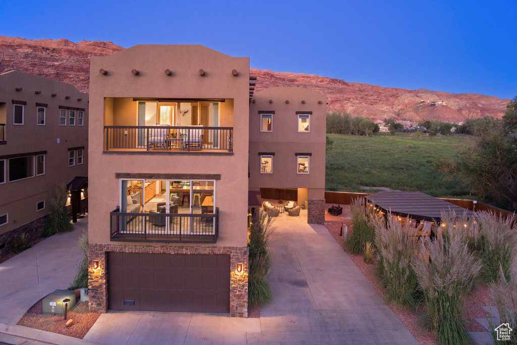 Pueblo-style house featuring a balcony, a garage, and a mountain view