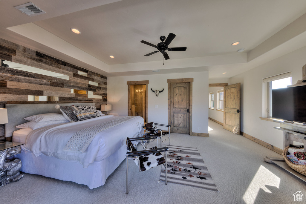 Bedroom with light carpet, ceiling fan, and a raised ceiling