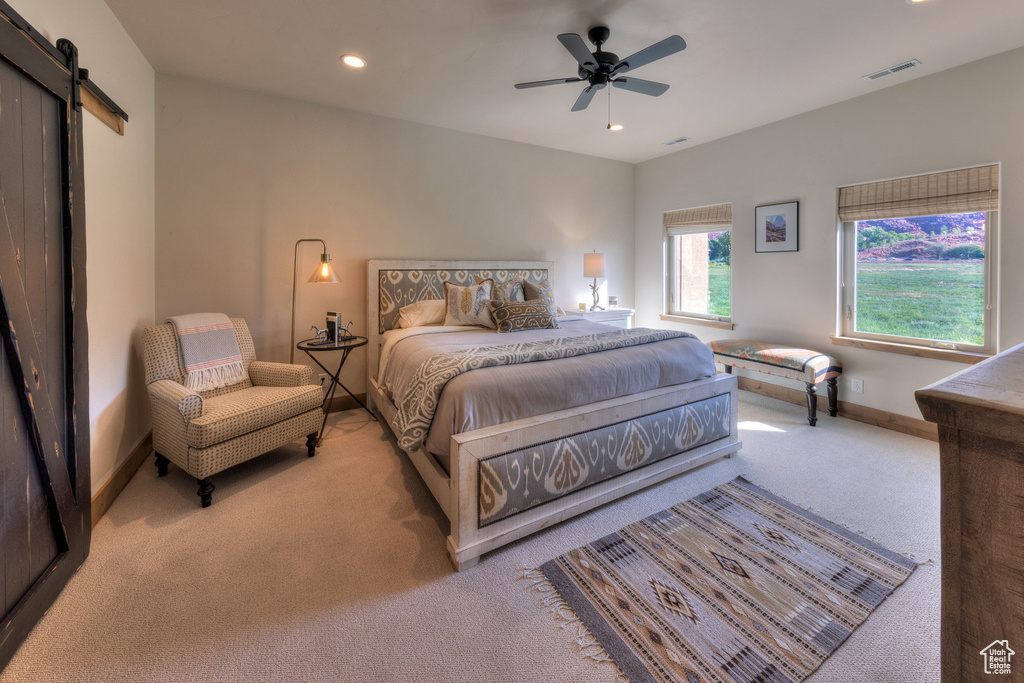 Carpeted bedroom with ceiling fan and a barn door