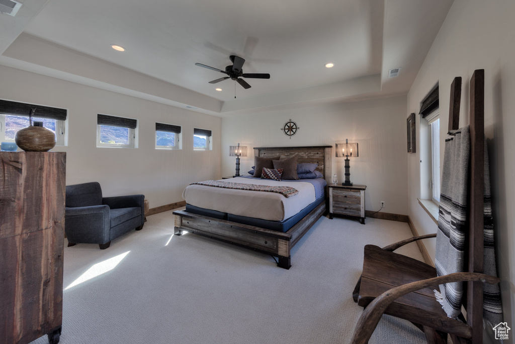 Bedroom with ceiling fan, a tray ceiling, and multiple windows
