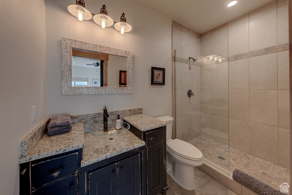 Bathroom with a tile shower, vanity, and toilet
