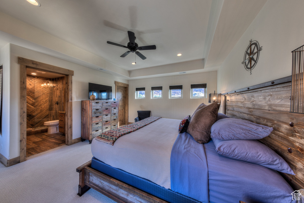 Carpeted bedroom with ensuite bath, ceiling fan, and wood walls