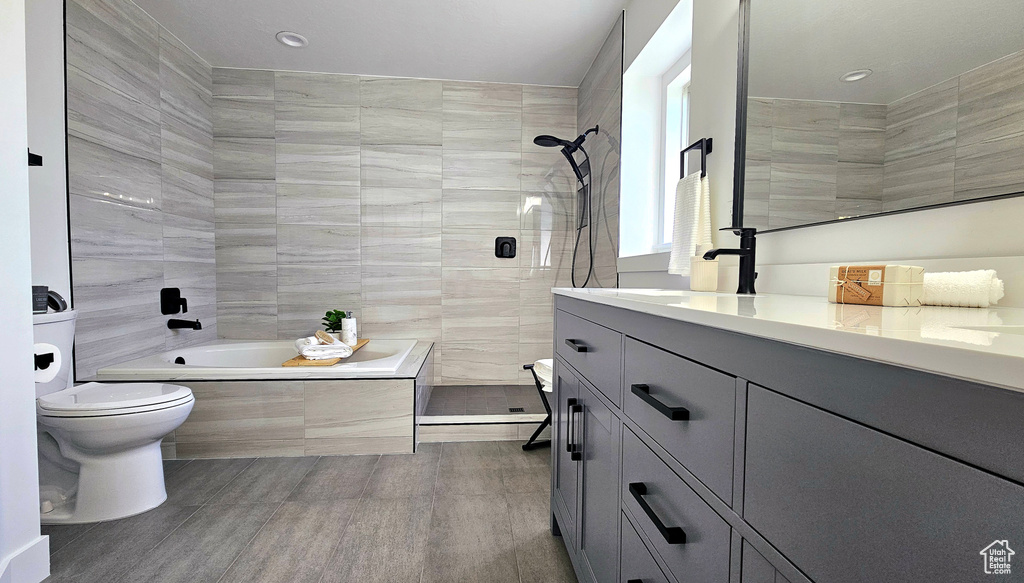 Full bathroom with wood-type flooring, tiled shower / bath, vanity, and toilet