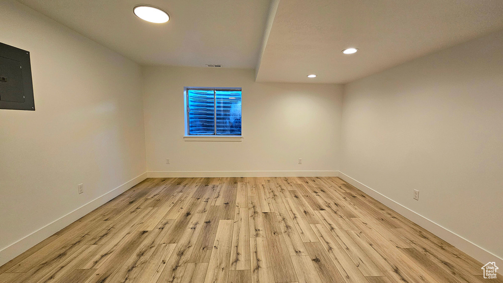 Spare room with electric panel and light hardwood / wood-style floors