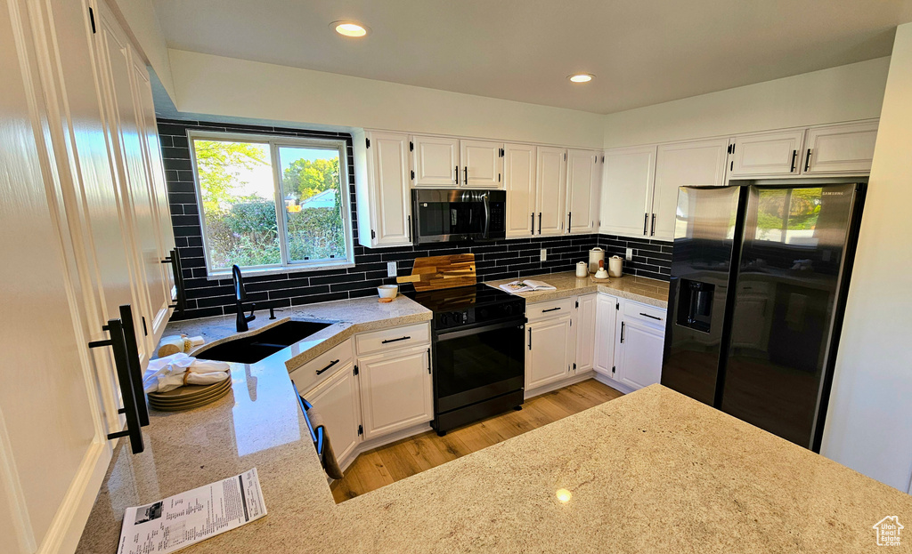 Kitchen featuring light hardwood / wood-style floors, white cabinetry, refrigerator with ice dispenser, sink, and electric range