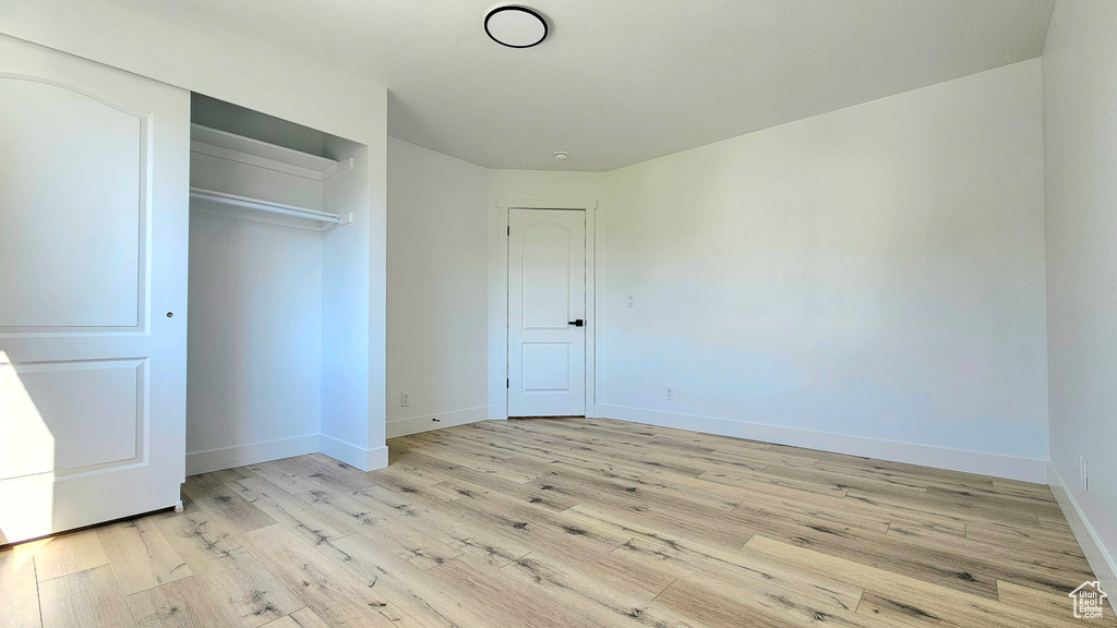 Unfurnished bedroom with a closet and light hardwood / wood-style floors