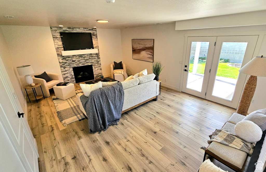 Living room with a stone fireplace and light wood-type flooring