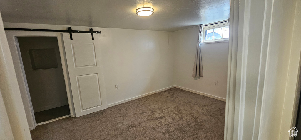 Carpeted empty room with a textured ceiling and a barn door