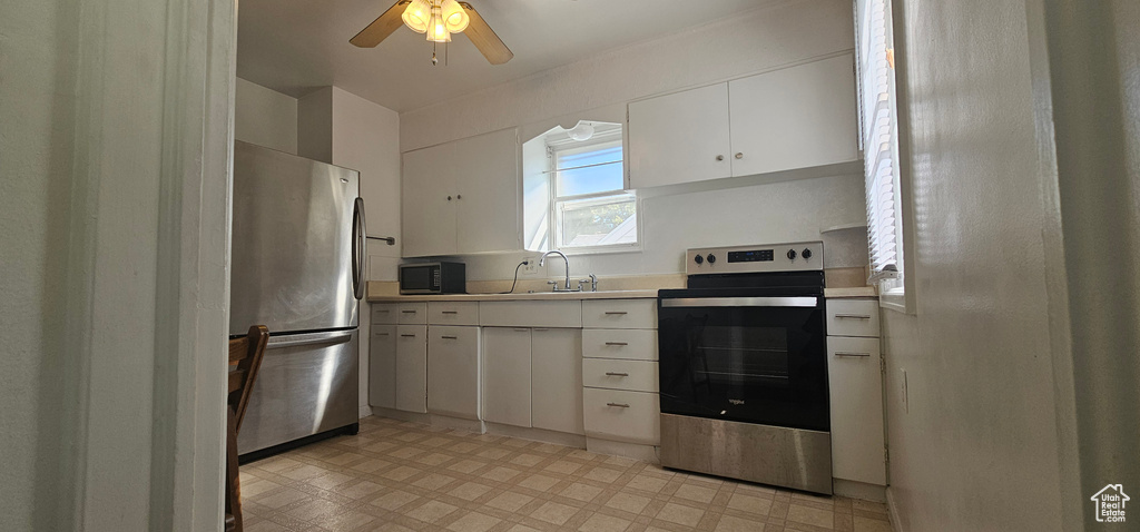 Kitchen with ceiling fan, white cabinets, appliances with stainless steel finishes, and sink