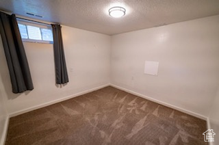 Unfurnished room featuring dark carpet and a textured ceiling