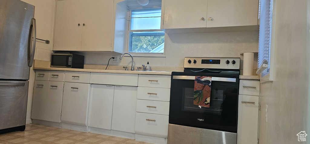 Kitchen featuring appliances with stainless steel finishes, white cabinetry, and sink