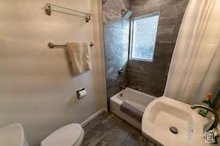 Full bathroom with toilet, shower / tub combo with curtain, and sink