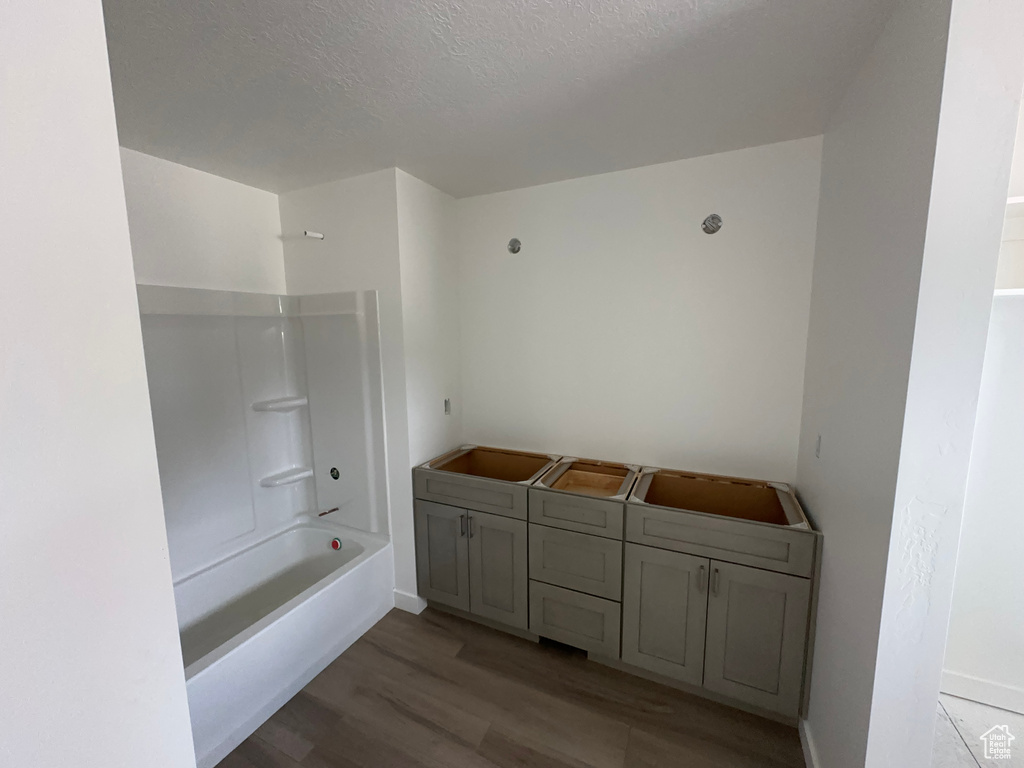 Bathroom with a textured ceiling, hardwood / wood-style floors, and shower / washtub combination