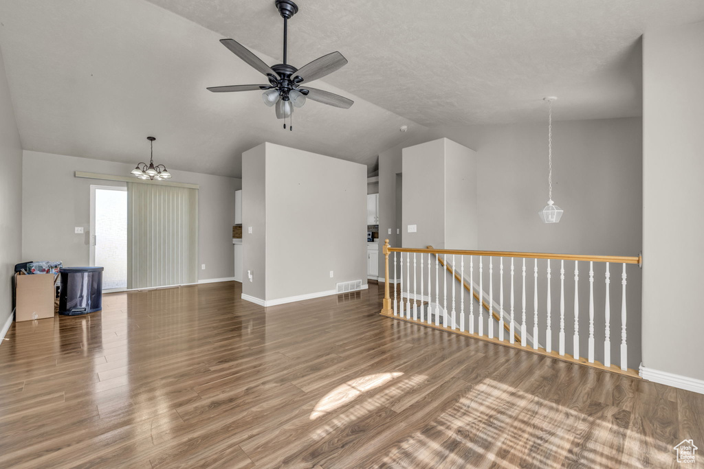 Interior space with ceiling fan with notable chandelier, a textured ceiling, lofted ceiling, and hardwood / wood-style floors