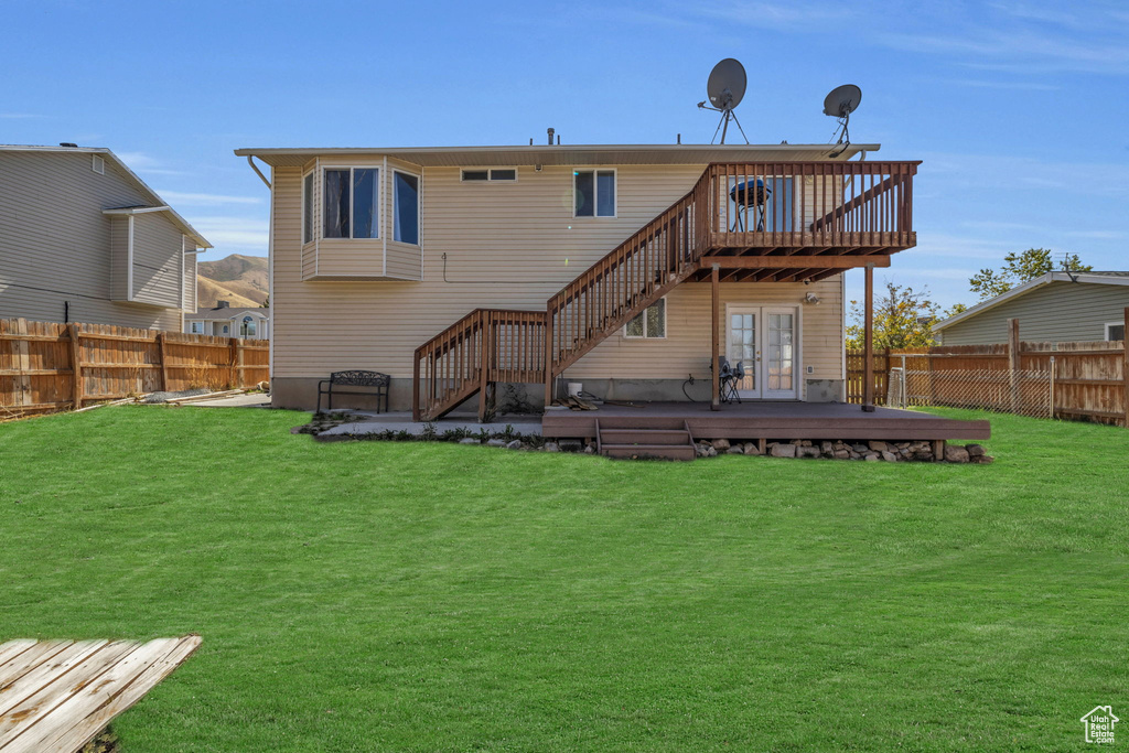 Back of house with a deck and a yard