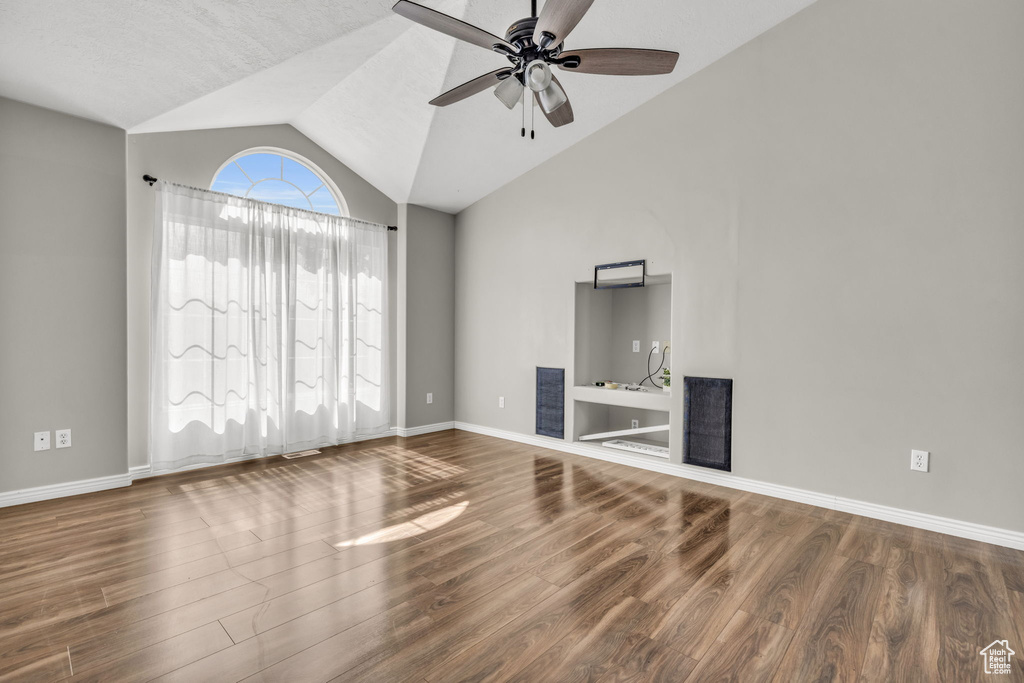 Unfurnished living room featuring a textured ceiling, lofted ceiling, ceiling fan, and hardwood / wood-style flooring